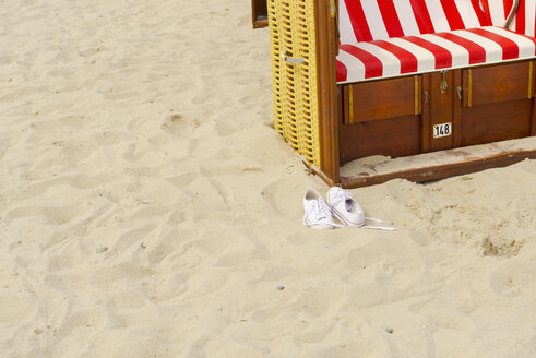 Ein Paar Turnschuhe und ein Strandkorb mit Kapuze am Strand - VIF000377