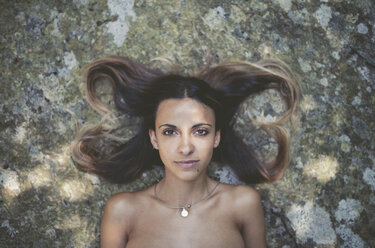 Porträt einer jungen Frau, die auf einem Felsen liegt - RAEF000427