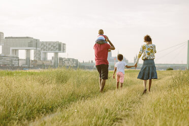 Germany, Cologne, family of four walking in a field - MADF000640