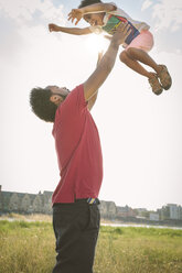 Germany, Cologne, father throwing up his son in a field - MADF000757