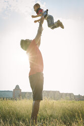 Germany, Cologne, father throwing up his son in a field - MADF000643