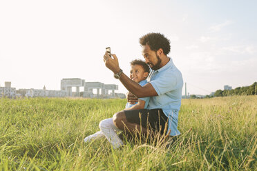 Deutschland, Köln, Vater und Sohn machen auf einem Feld ein Selfie - MADF000652