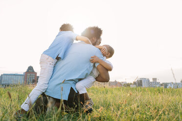 Germany, Cologne, playful father with two sons in field - MADF000659