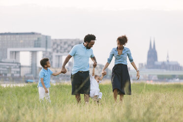 Germany, Cologne, family of four walking in a field - MADF000666