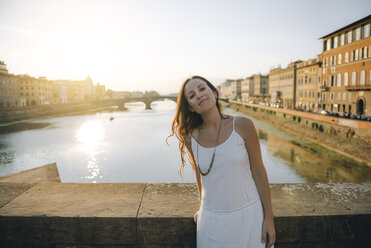 Italien, Florenz, Porträt einer Frau in weißem Sommerkleid auf einer Brücke bei Sonnenuntergang - GEMF000326