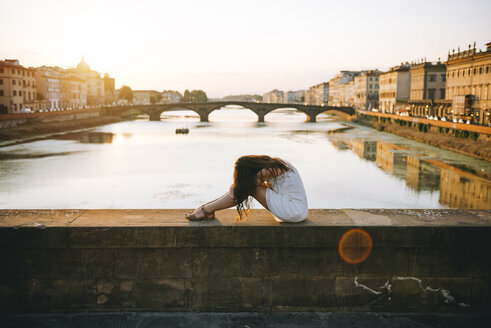 Italien, Florenz, Frau in weißem Sommerkleid entspannt auf einer Brücke bei Sonnenuntergang - GEMF000331