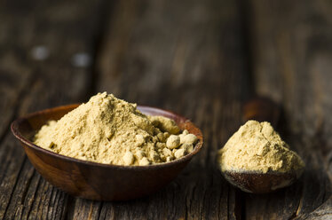 Wooden bowl and spoon with ginger powder on dark wood - ODF001235