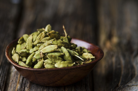 Wooden bowl with cardamom capsules stock photo