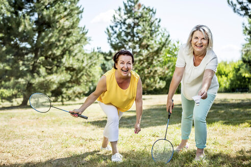 Zwei glückliche reife Frauen auf einer Wiese spielen Badminton - RKNF000184