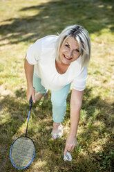 Lächelnde reife Frau auf einer Wiese beim Badminton spielen - RKNF000186