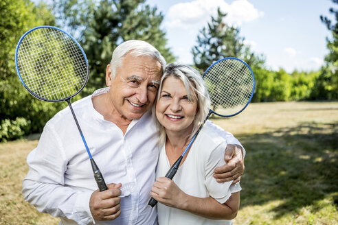 Porträt eines lächelnden älteren Paares auf einer Wiese mit Badmintonschlägern - RKNF000190