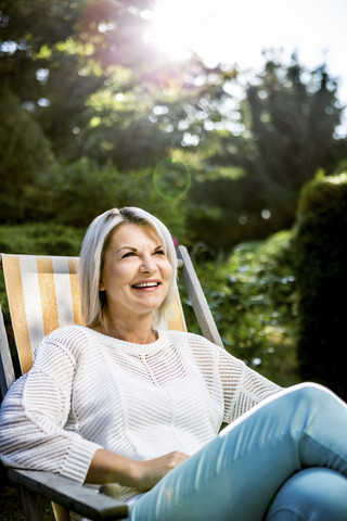 Ältere Frau entspannt im Liegestuhl im Garten, lizenzfreies Stockfoto