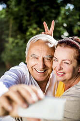 Verspieltes älteres Paar macht ein Selfie im Freien - RKNF000264