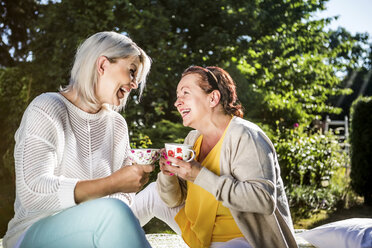 Glückliche reife Frauen im Garten mit Kaffeetassen - RKNF000269