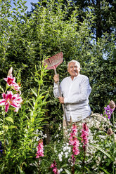 Älterer Mann mit Harke im Garten stehend - RKNF000301