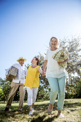 Glückliche ältere Freunde auf einer Wiese mit Decke und Picknickkorb - RKNF000338