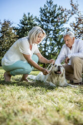 Älteres Paar mit Hund auf einer Wiese - RKNF000367