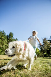 Ältere Frau mit Hund auf einer Wiese - RKNF000370