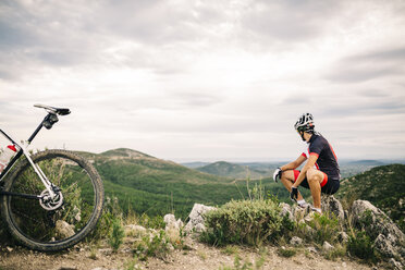 Spain, Tarragona, Mountain biker having a break in extreme terrain - JRFF000027