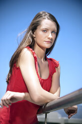 Portrait of young woman leaning on railing - TOYF001332