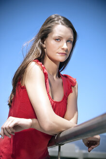 Porträt einer jungen Frau, die sich an ein Geländer lehnt - TOYF001332