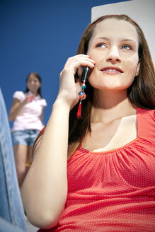 Smiling young woman on cell phone in sunshine - TOYF001336