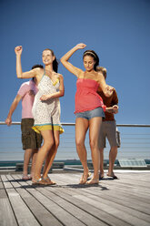 Happy friends dancing on wooden terrace - TOYF001345