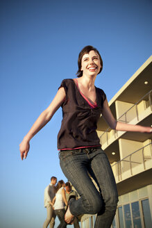 Glückliche junge Frau beim Laufen mit Freunden im Hintergrund - TOYF001366
