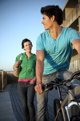 Junger Mann mit Fahrrad und Frau, die ihm folgt - TOYF001395
