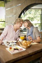 Lächelndes älteres Ehepaar, das sich beim Frühstück in einem Café gegenübersteht - TOYF001263