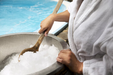 Woman with wooden spoon in ice bucket in a spa - TOYF001299