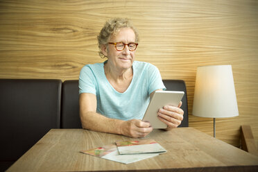 Lächelnder älterer Mann in einem Café mit digitalem Tablet - TOYF001308