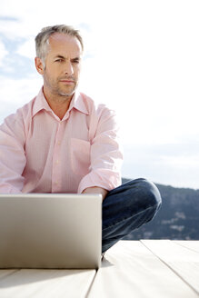 Portrait of serious looking man with laptop - TOYF001172