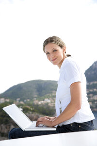 Spanien, Mallorca, Porträt einer lächelnden Frau mit Laptop - TOYF001184