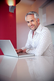 Portrait of smiling man with laptop - TOYF001402
