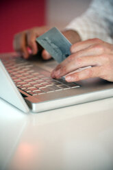 Man using laptop and holding credit card, close-up - TOYF001231