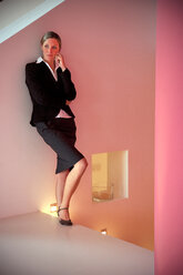 Portrait of pensive businesswoman leaning on a wall - TOYF001405