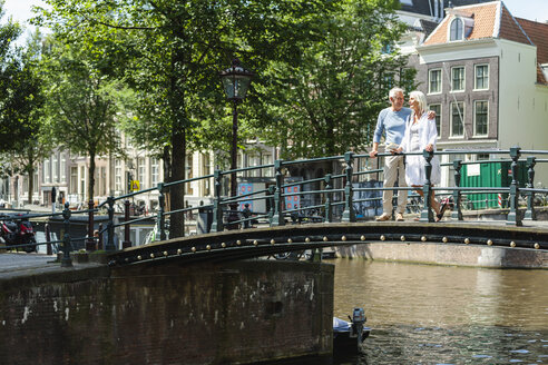 Niederlande, Amsterdam, älteres Paar beim Spaziergang auf einer Brücke - FMKF002062