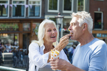 Niederlande, Amsterdam, glückliches älteres Paar isst Pommes frites - FMKF002050