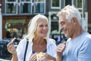 Niederlande, Amsterdam, glückliches älteres Paar isst Pommes frites - FMKF002049