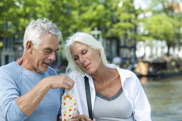 Netherlands, Amsterdam, senior couple eating French Fries - FMKF002045