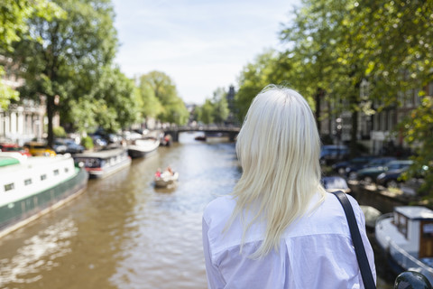 Niederlande, Amsterdam, ältere Frau schaut auf Stadtkanal, lizenzfreies Stockfoto