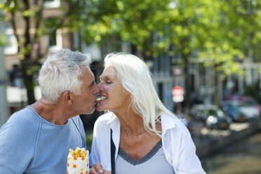Niederlande, Amsterdam, glückliches älteres Paar, das Pommes frites teilt - FMKF002040