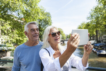 Netherlands, Amsterdam, senior couple taking a selfie at town canal - FMKF002035