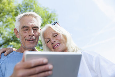 Senior couple looking at digital tablet outdoors - FMKF002031