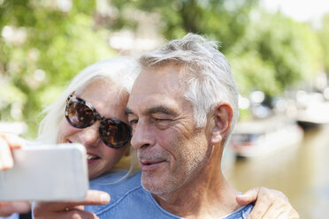 Netherlands, Amsterdam, senior couple taking a selfie at town canal - FMKF002028