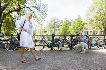Niederlande, Amsterdam, älterer Mann fotografiert seine Frau auf einer Brücke - FMKF002018