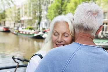 Netherlands, Amsterdam, happy senior couple hugging at town canal - FMKF002013