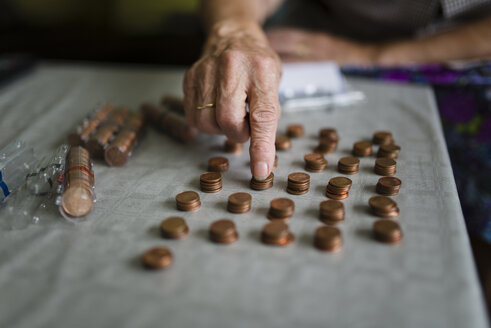 Elderly woman counting money, making stacks of Euro cents - RAEF000410