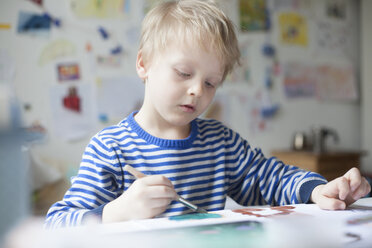 Porträt eines blonden kleinen Jungen, der mit Aquarellfarben malt - RBF002998